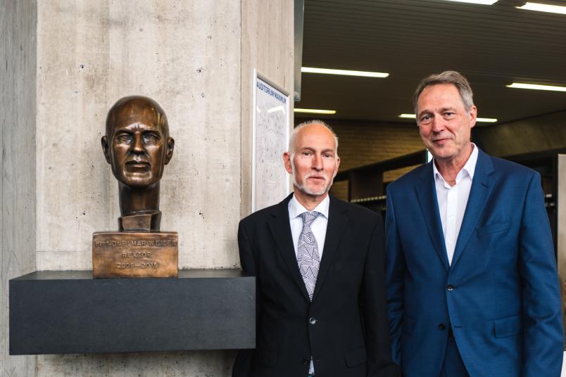 Rektor Axel Schölmerich (rechts) und Altrektor Elmar Weiler mit dem Kunstwerk