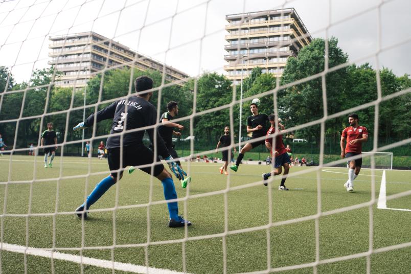 Fußballspieler auf dem Platz durch das Tornetz fotografiert