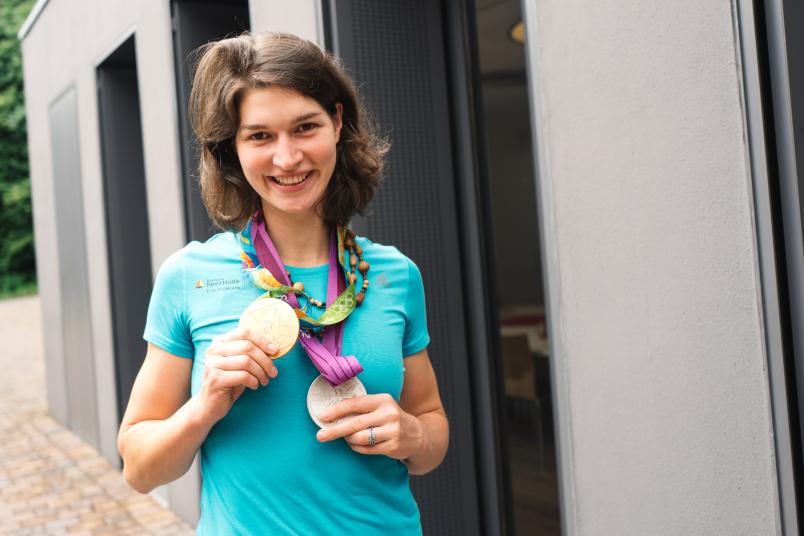 Eine Frau hat eine Goldmedaille und eine Silbermedaille um den Hals hängen.