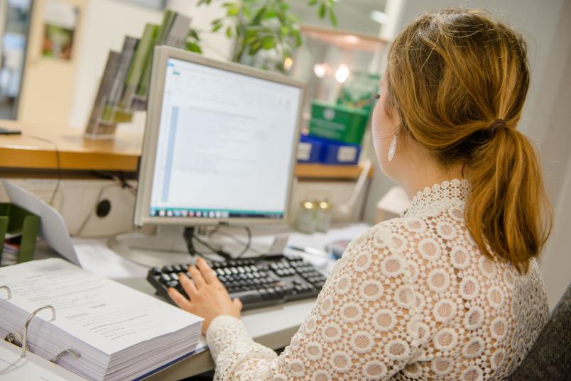 Junge Frau sitzt vor einem Computer.