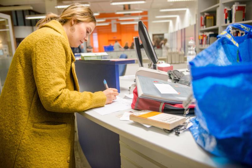 Frau trägt etwas in eine Liste ein.