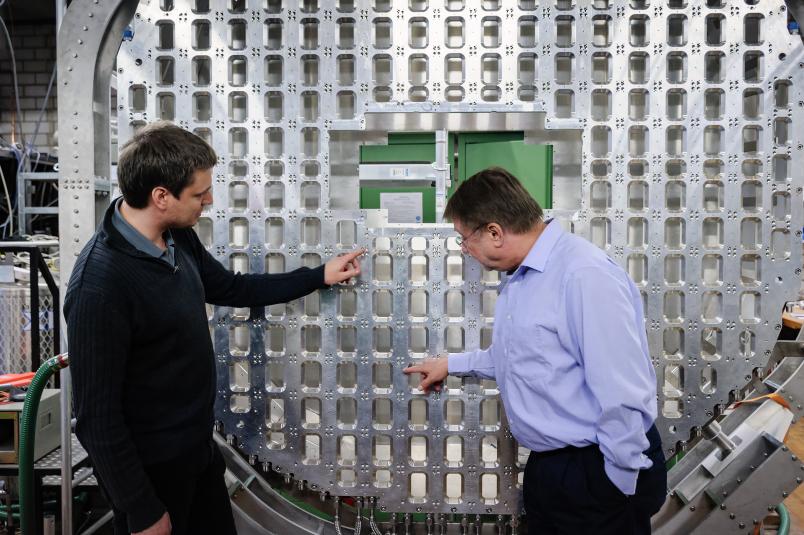 Zwei Forscher begutachten eine große Metallkonstruktion.