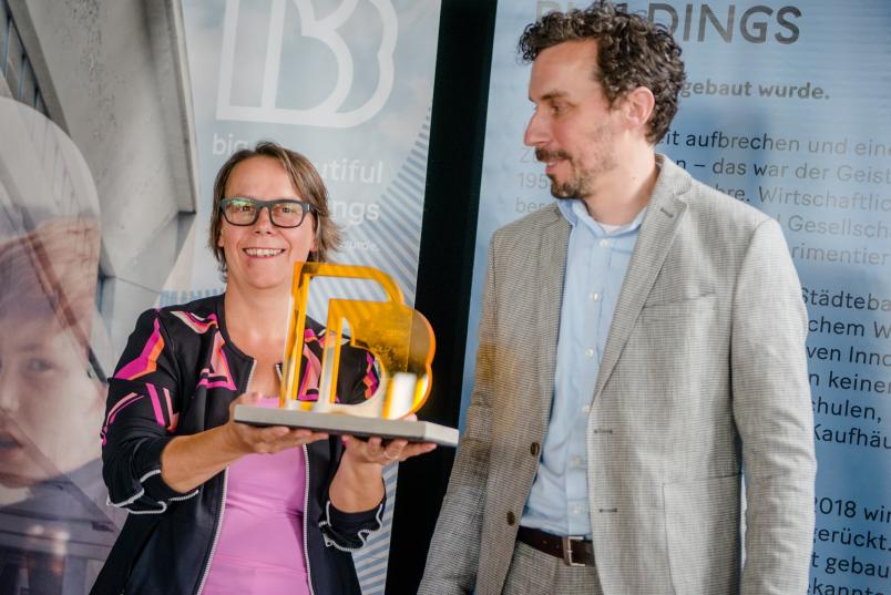 Tim Rieniets, Geschäftsführer der Landesinitiative Stadtbaukultur NRW, überreicht Kanzlerin Christina Reinhardt den Wanderpokal zur Auszeichnung Big Beautiful Buildings.