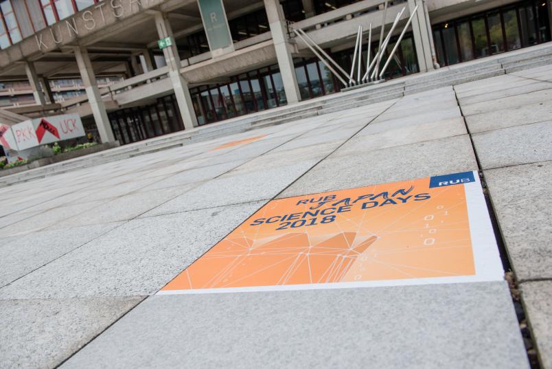Für die Gäste aus Japan sind auch einzelne Bodenplatten auf dem Forum mit dem Key Visual der ersten RUB Japan Science Days beklebt worden.