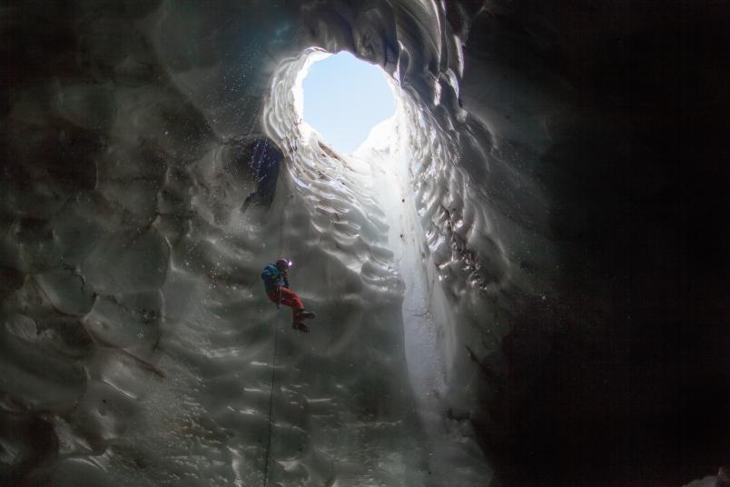 Ein Mann seilt sich in eine Eishöhle ab.