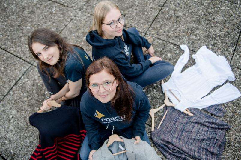 Drei Studentinnen sitzen auf dem Boden. 