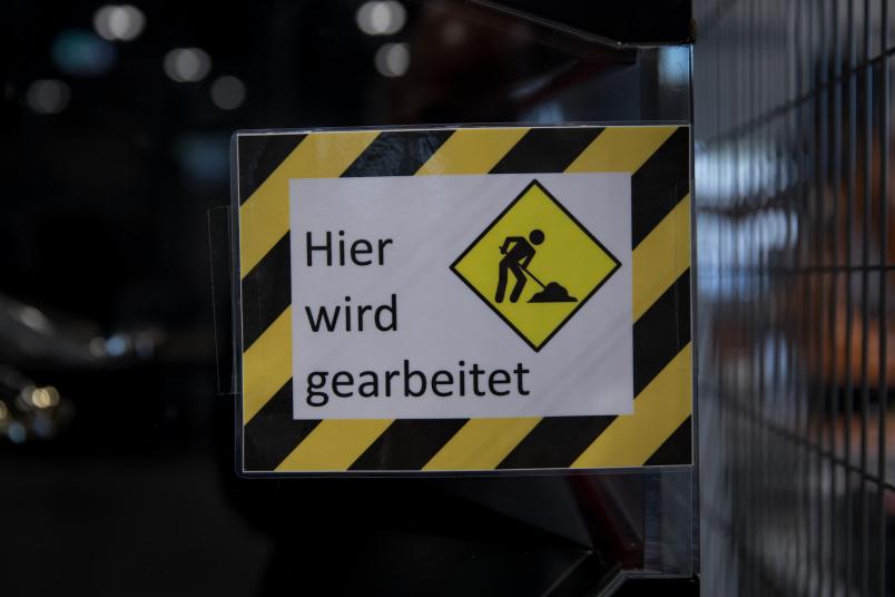 Ein schwarz-gelbes Schild: "Hier wird gearbeitet."