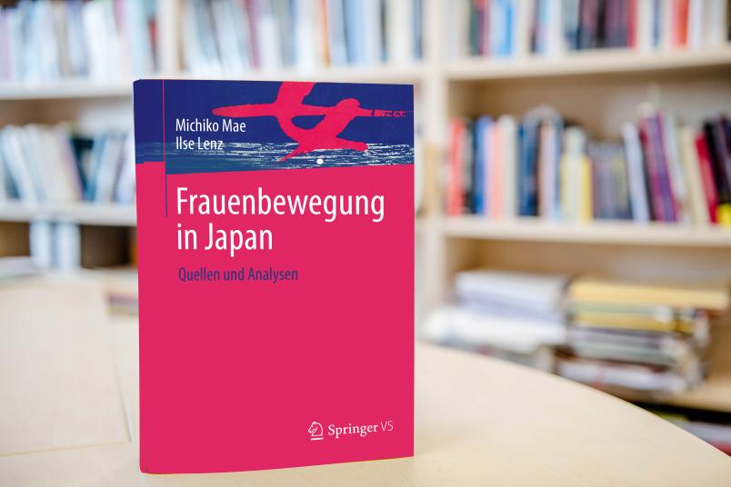 Buch auf Tisch vor Bücherregal