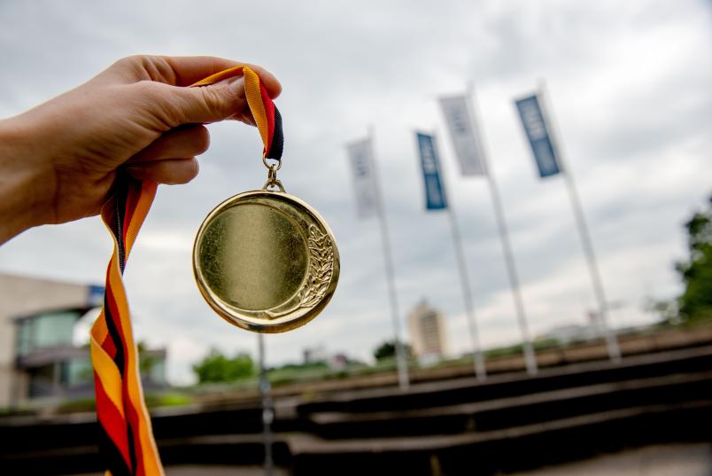 Eine Hand hält eine Goldmedaille