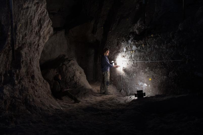 Mann in dunkler Höhle mit Taschenlampe