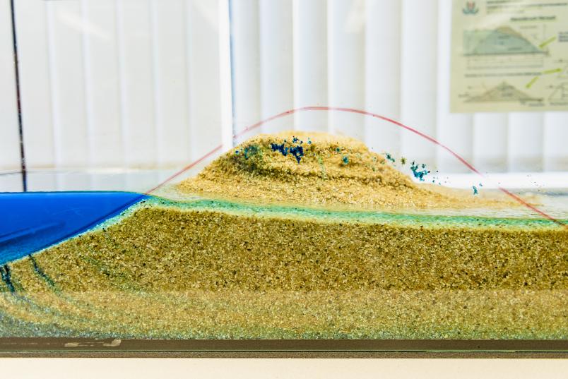 Künstlicher Sanddeich mit Wasser in einem Glaskasten