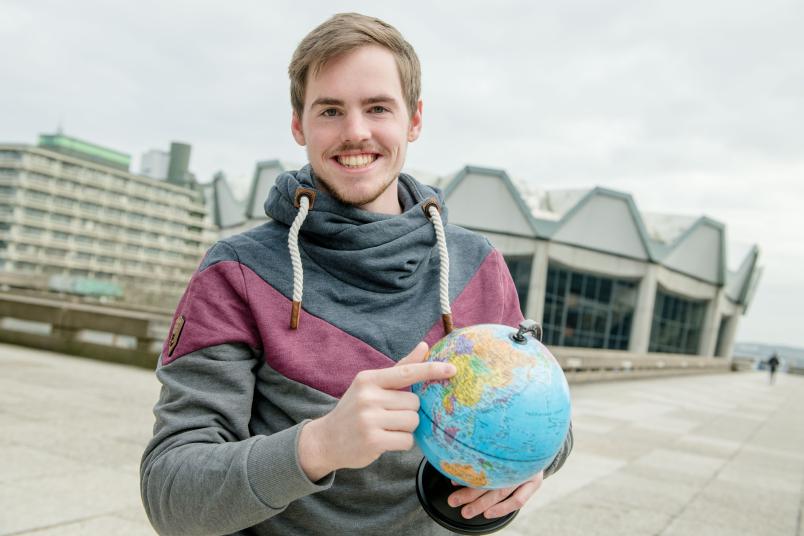Student mit Weltkugel in der Hand.