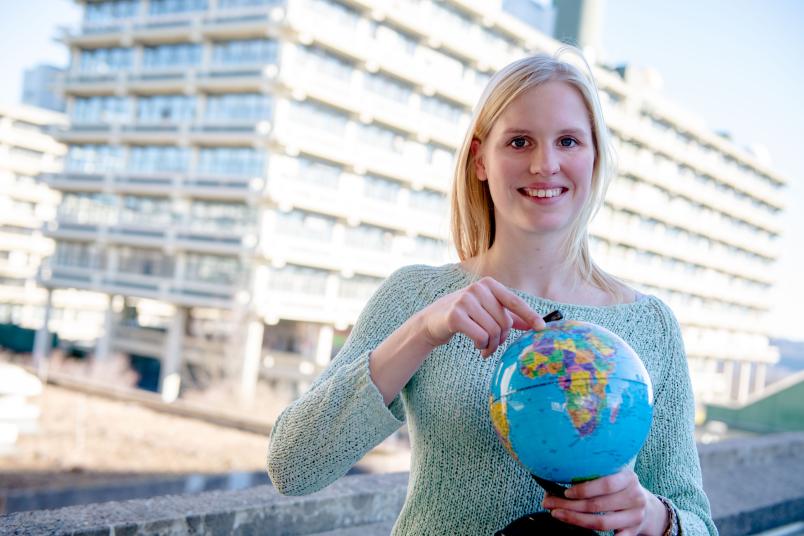Studentin mit Globus vor RUB-Kulisse