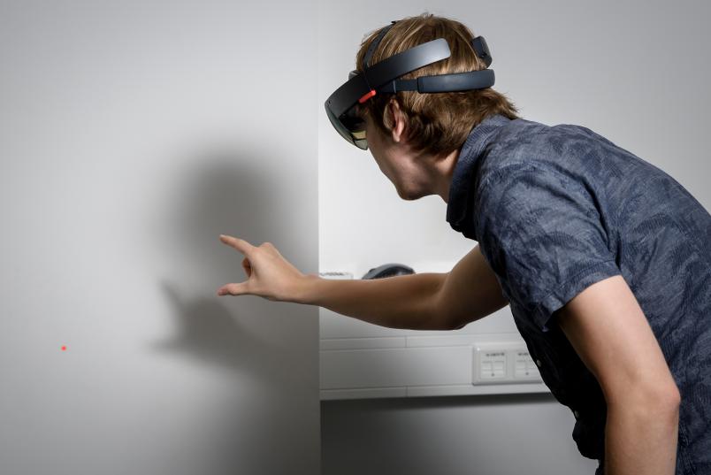 Hand greift nach rotem Punkt an Wand