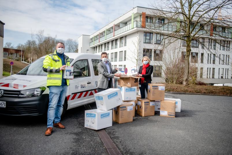 Atemschutzmasken und Schutzanzüge, die an der RUB derzeit nicht gebraucht werden, hat Olaf Kraft (links) zum St. Josef-Hospital gebracht. Dr. Jürgen Frech, Leiter der Unternehmenskommunikation, und Irmgard Plößl freuen sich über die Materialien.