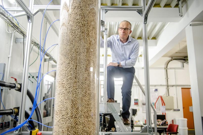 Mann steht auf Tisch neben Forschungsaufbau