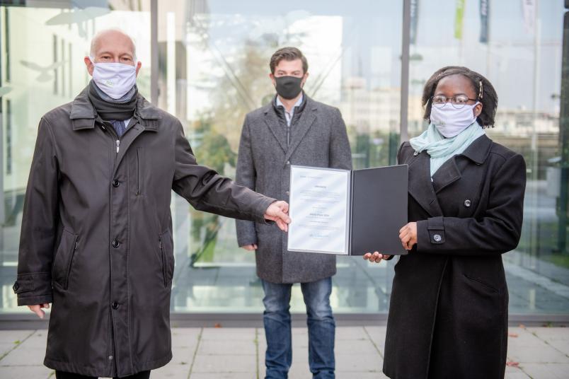 Übergabe einer Urkunde. Personen von links nach rechts: Elmar Weiler, Christoph Baer, Ngole Noumegne.