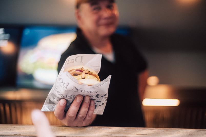 Ein Mann hält einen Burger in die Kamera