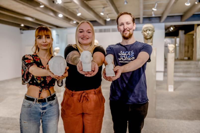 Drei Studierende mit Büsten aus 3D-Druckverfahren in den Händen.