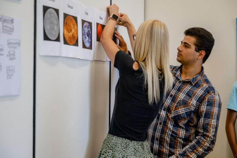 Studentin und Schüler stehen an einer Wand. 