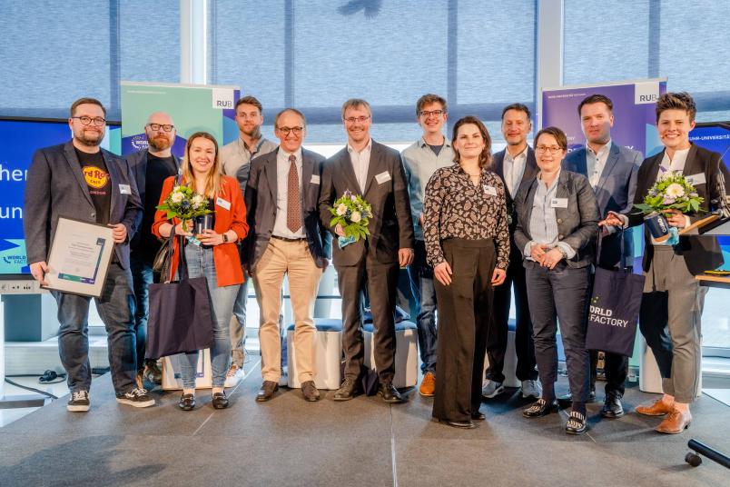 Auf der Bühne steht eine Gruppe von Personen mit Blumensträußen und Urkunden.