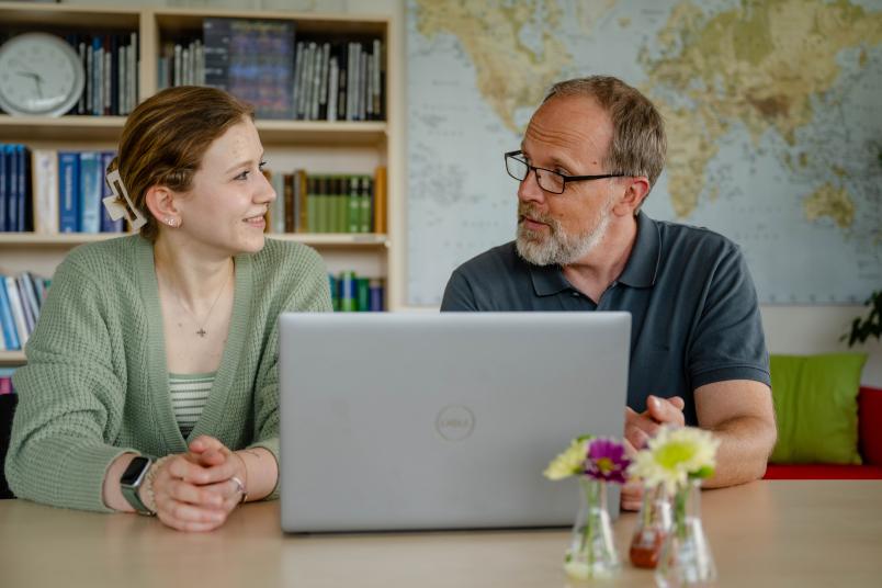 Junge Frau und Mann schauen auf einen Laptop