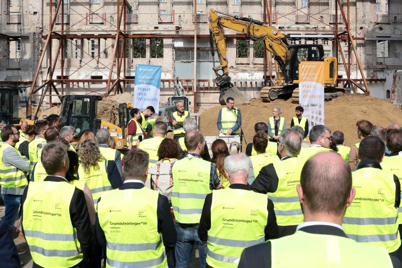 Eine Person hält eine Rede auf einer Baustelle
