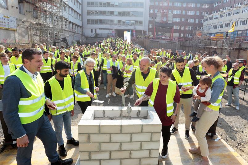 Viele Personen in Warnwesten auf einer Baustelle