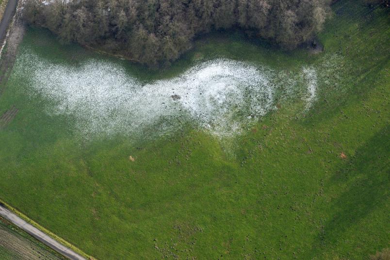 Luftbild einer Wiese mit etwas Schnee, in der Spuren eines Gebäudes erkennbar sind