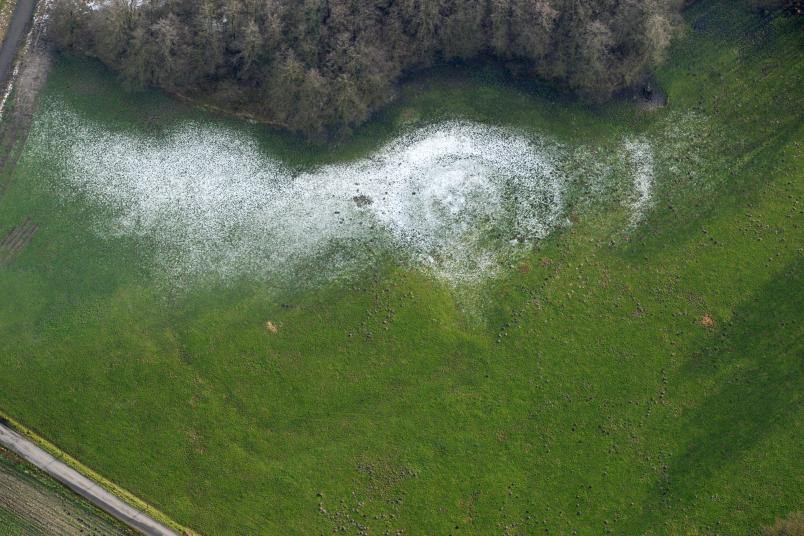 Luftbild einer Wiese mit etwas Schnee, in der Spuren eines Gebäudes erkennbar sind