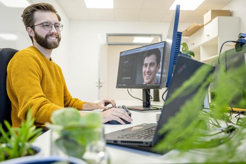 Eine Person vor einem Computermonitor, auf dem ein Porträt zu sehen ist