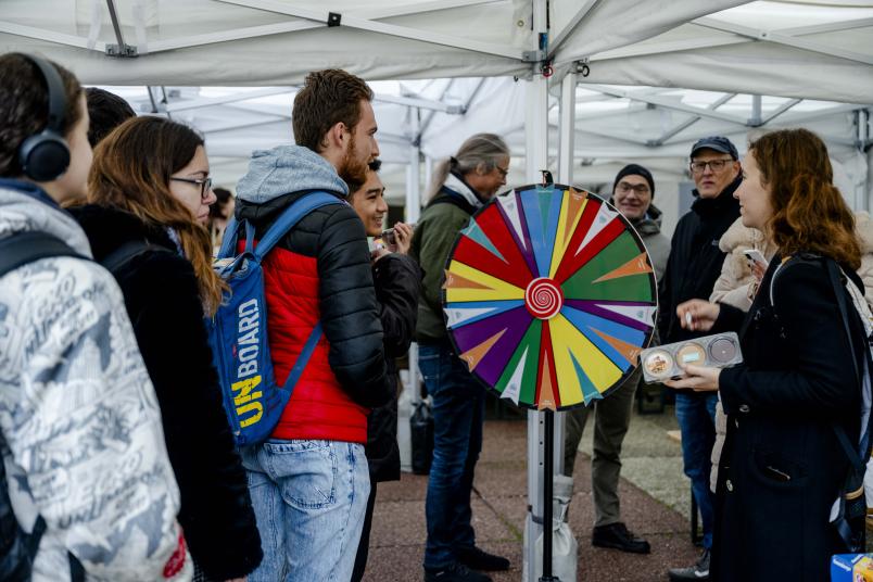 Gruppe von Leuten steht um ein buntes Glücksrad herum.