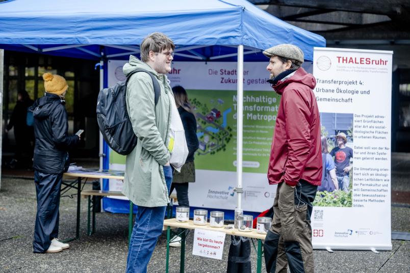 zwei Männer unterhalten sich vor einem Zeltstand
