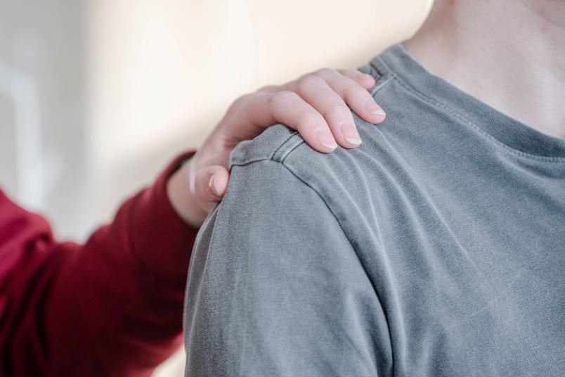 Hand berührt jemanden an der Schulter