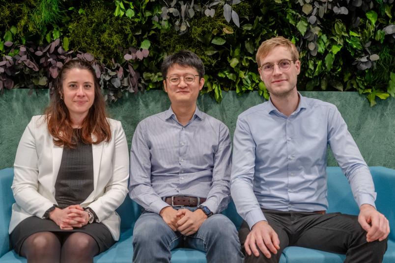 Célia Millon, Yicheng Wang und Michael Müller sitzen auf einer Bank im Foyer des Gebäudes UV.