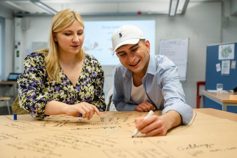 Zwei Studierende schreiben etwas auf. 
