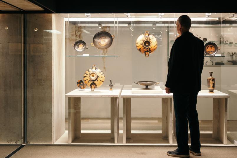 Eine Person vor einer Vitrine mit Gegenständen