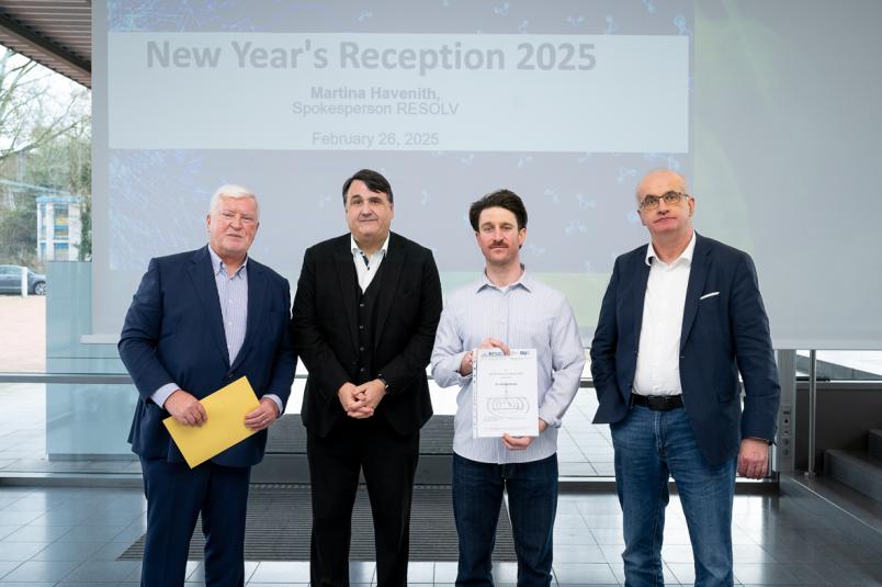 Gruppenfoto, in der Mitte eine Person mit Urkunde