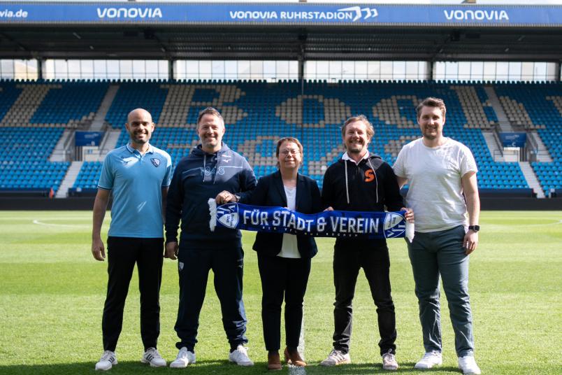 Gruppenbild im Stadion mit 5 Personen, die gemeinsam einen VfL-Bochum-Schal zeigen