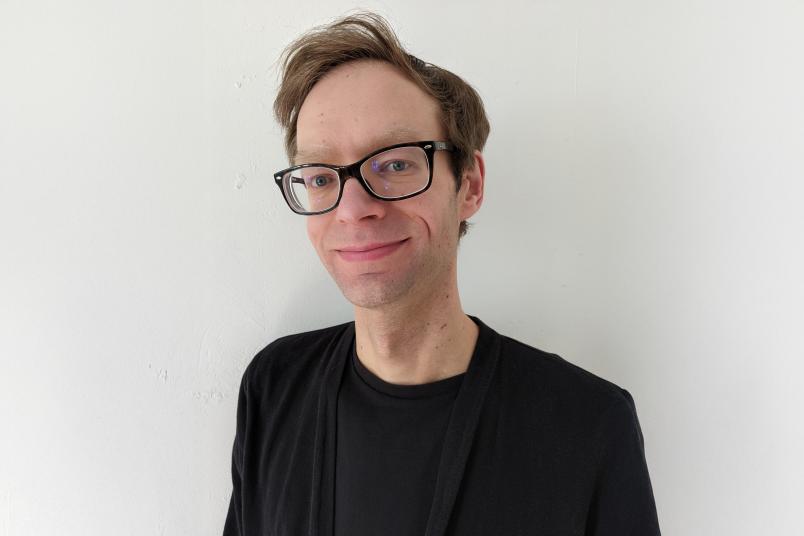 Porträt eines jungen Mannes mit blonden kurzen Haaren, Brille und schwarzem Shirt