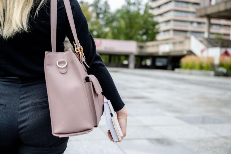 Studentin trägt Tasche und Bücher. 