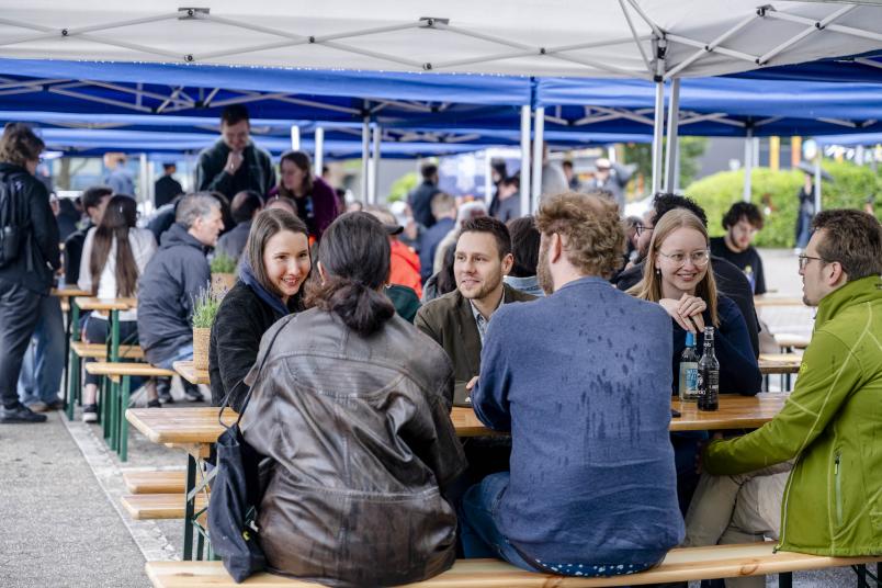 Mehrere Personen sitzen an einer Bierzeltgarnitur