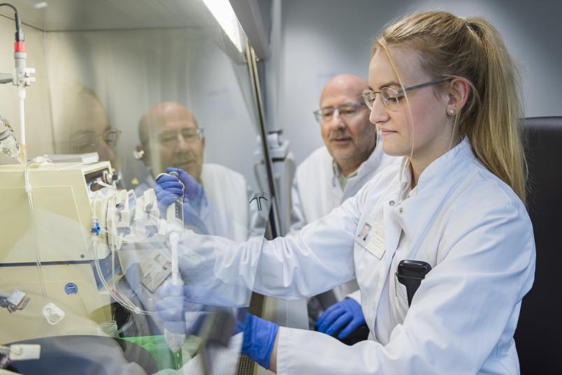 Eine Frau pipettiert hinter einem Abzug