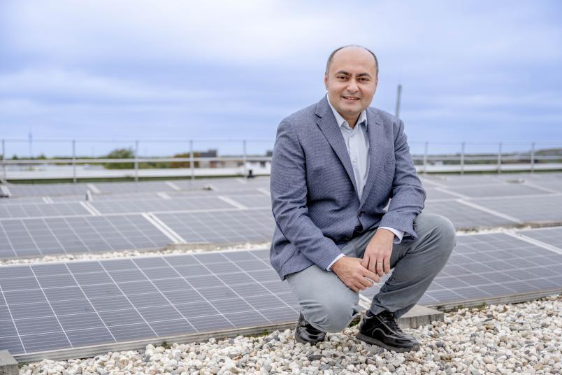 Porträt des Forschers, der vor einer Solaranlage hockt