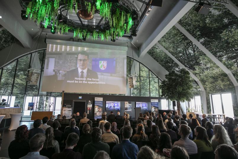 Nordrhein-Westfalens Ministerpräsident Hendrick Wüst richtet sich in einer Videobotschaft an das Publikum.