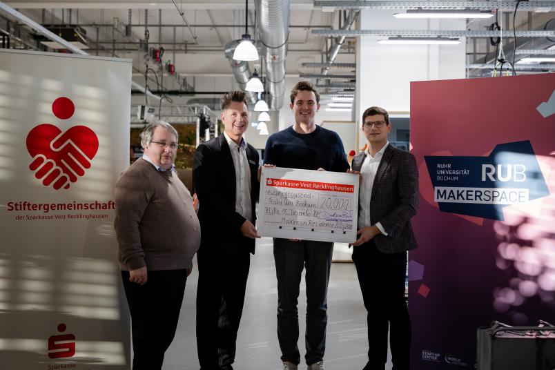 Vier Personen im Makerspace der Ruhr-Universität Bochum bei einer Scheckübergabe