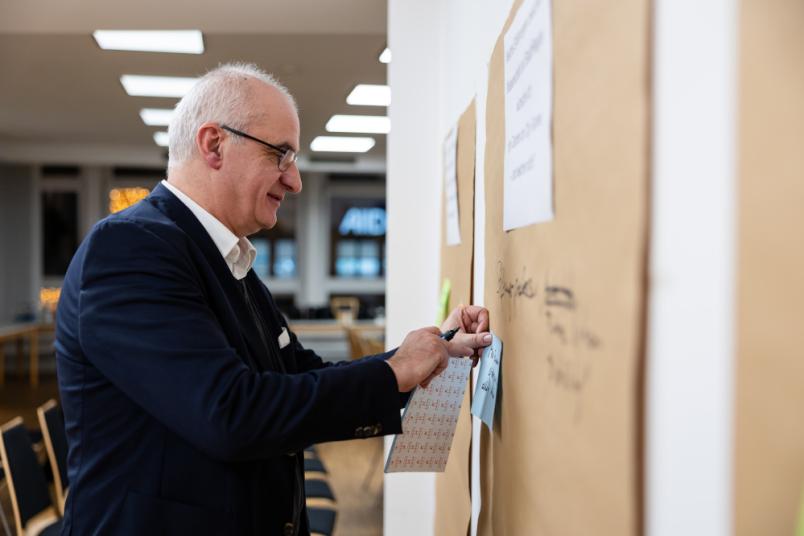 Mann pinnt Karte an eine Pinnwand. 