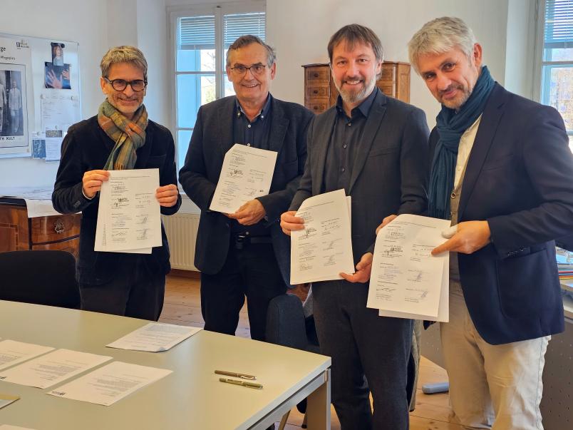 Vier Personen mit einem unterzeichneten Dokument in den Händen