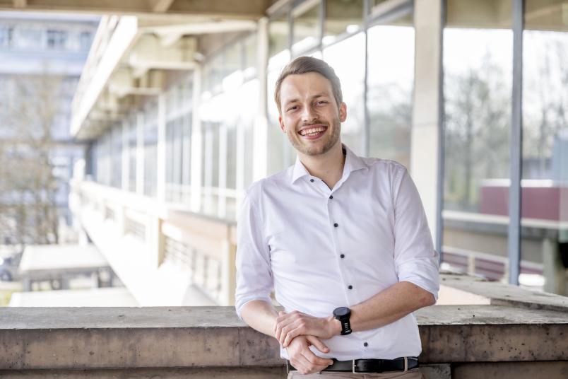 Mann im weißen Hemd lehnt an einer Brüstung und lacht