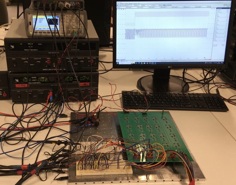 Platine mit vielen Kabeln und Computermonitor mit Oszillationen